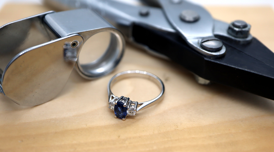 Trilogy Engagement Ring, a loupe and pliers